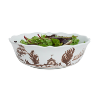 Decorative salad bowl with brown patterns filled with green salad on a white background
