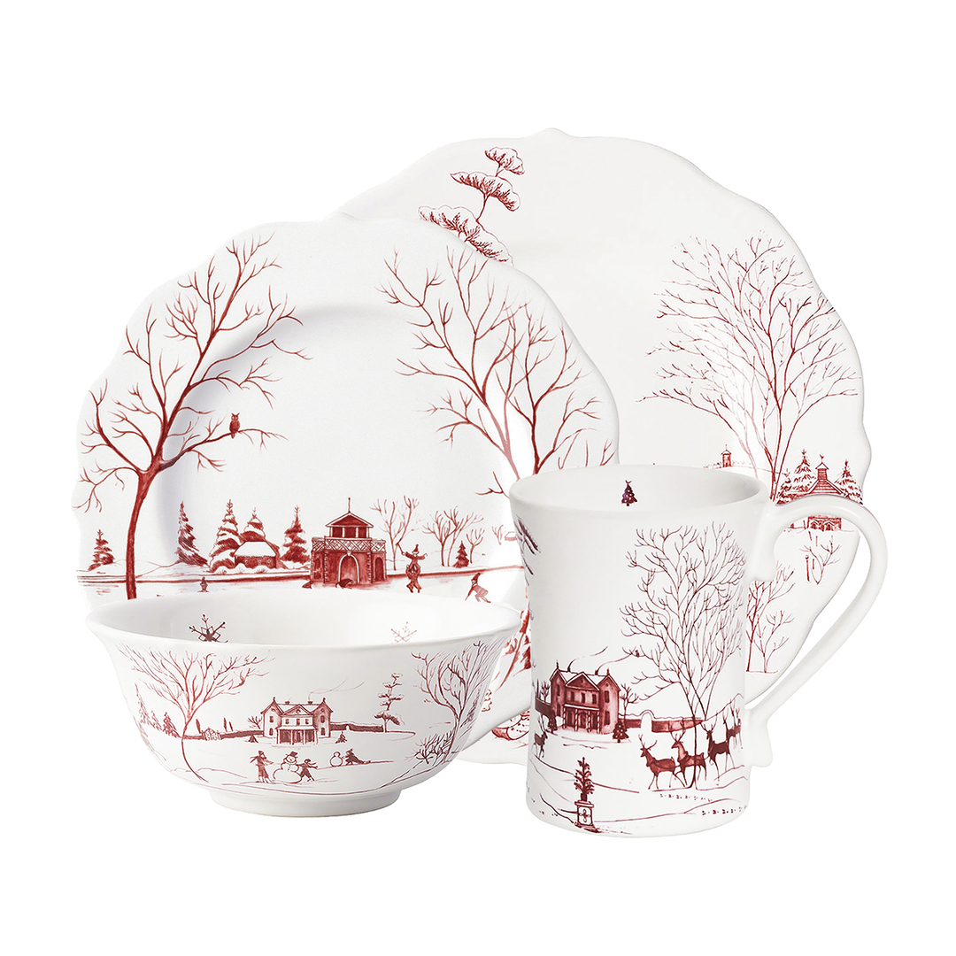 A set of porcelain dishware including a dinner plate, salad plate, pasta bowl, and mug decorated with a red winter scene