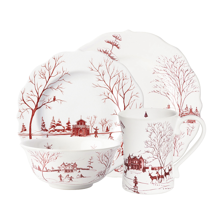 A set of porcelain dishware including a dinner plate, salad plate, pasta bowl, and mug decorated with a red winter scene