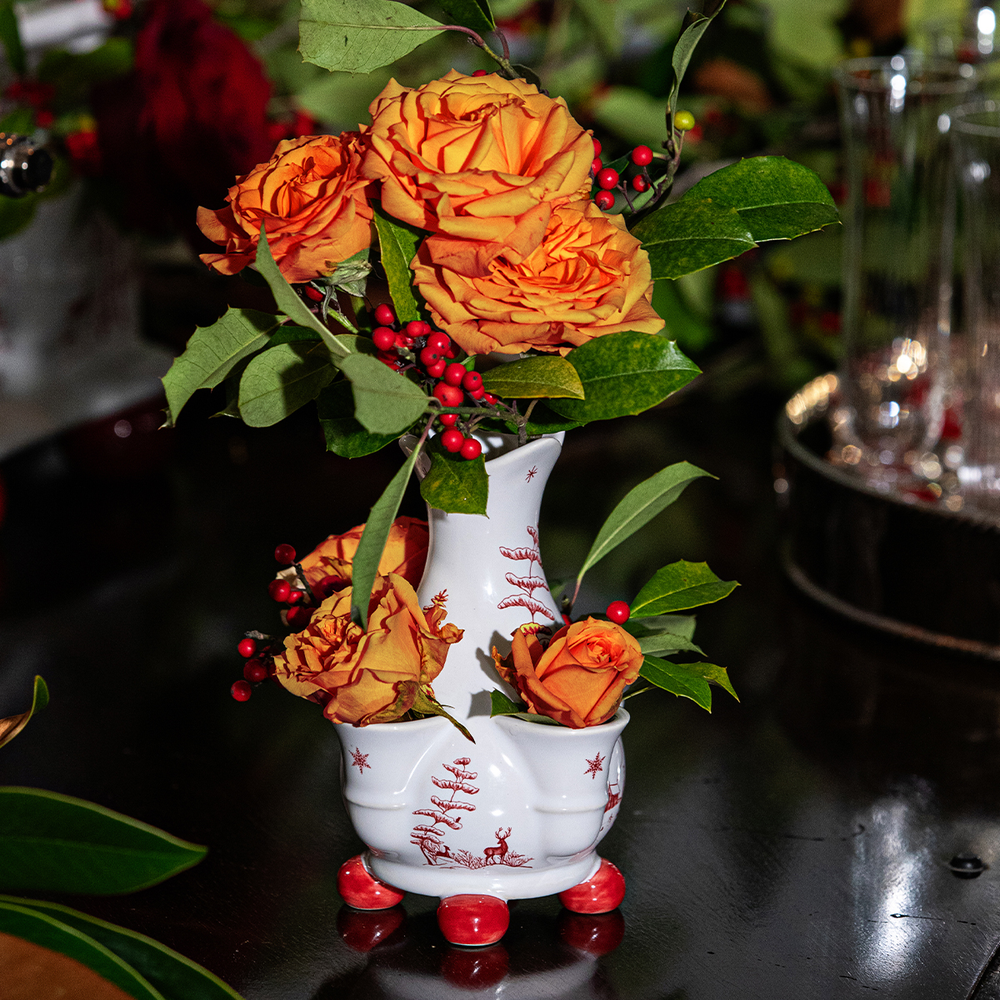 Decorative vase with orange flowers and red berries on a dark surface