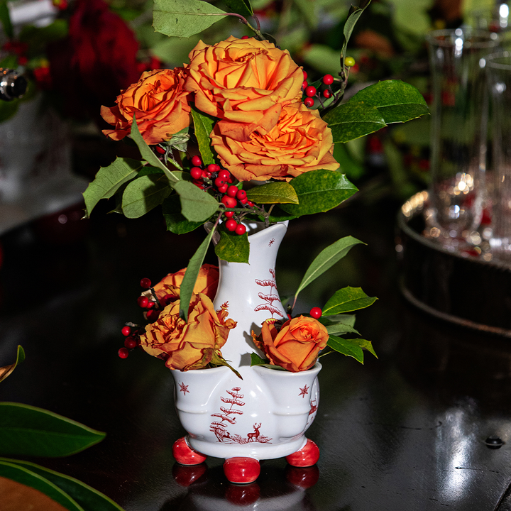 Decorative vase with orange flowers and red berries on a dark surface