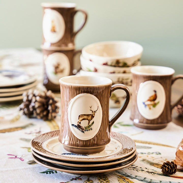 Set of ceramic mugs and plates with deer design on a table