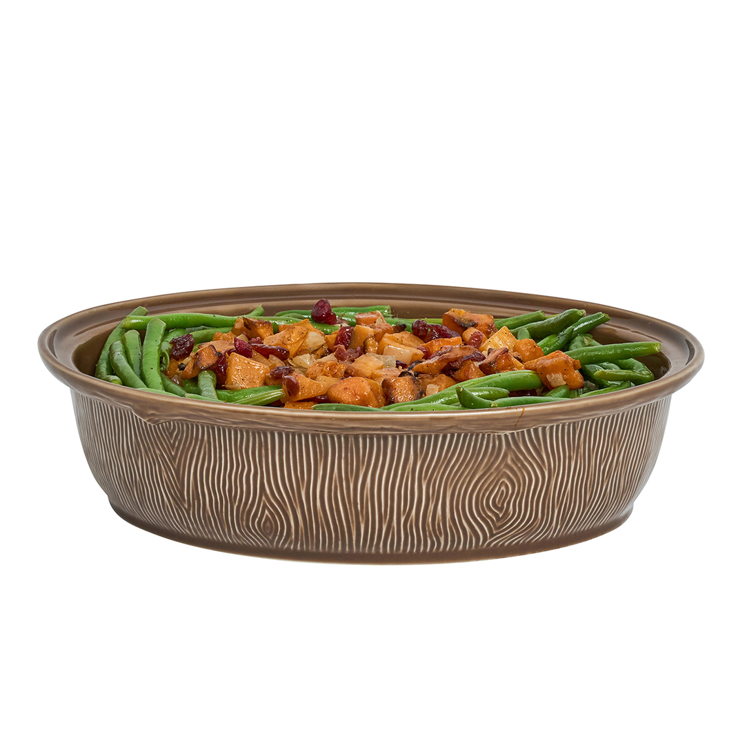 An oval ceramic casserole dish with a brown wood-grain textured exterior, filled with green beans and sweet potato casserole
