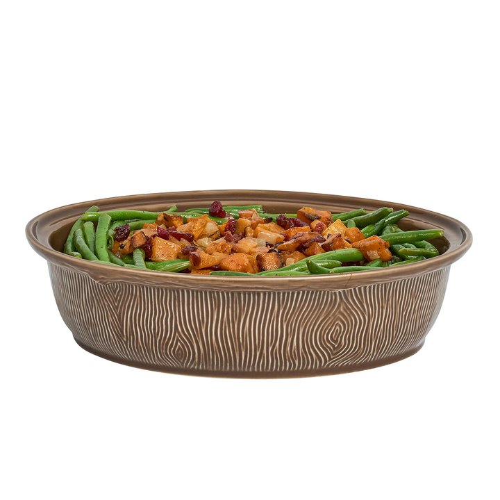 An oval ceramic casserole dish with a brown wood-grain textured exterior, filled with green beans and sweet potato casserole