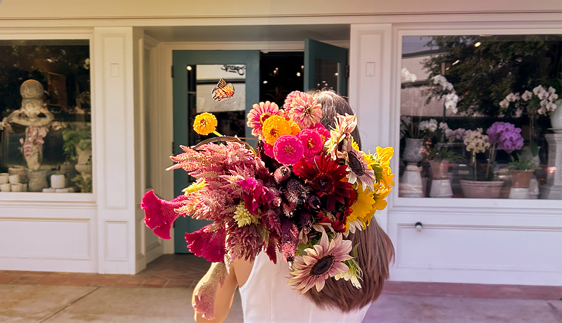 A florist holding a large bouquet of colorful flowers with a butterfly in front of Charleston Street