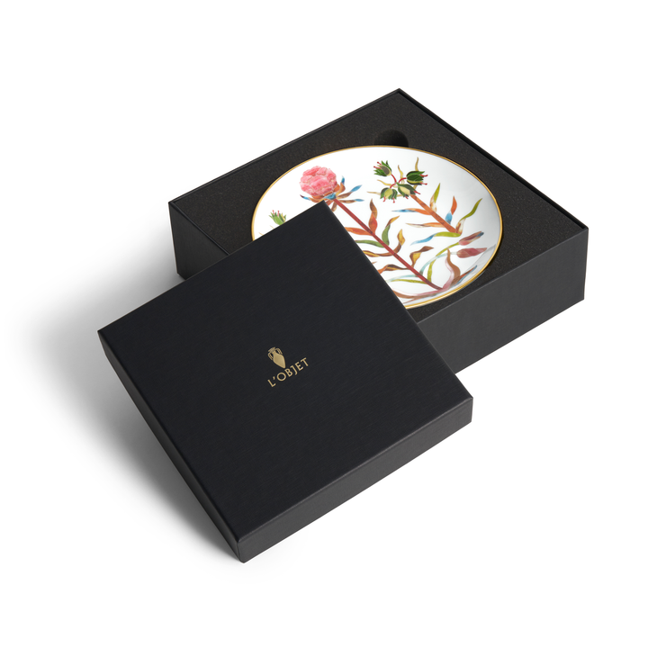 A L'Objet box with the lid moved aside to reveal a white porcelain plate with floral designs