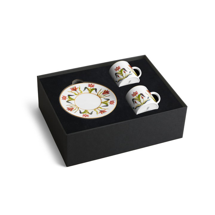 A set of two porcelain  coffee cups with matching saucers painted with floral designs and rimmed with gold in a black box 