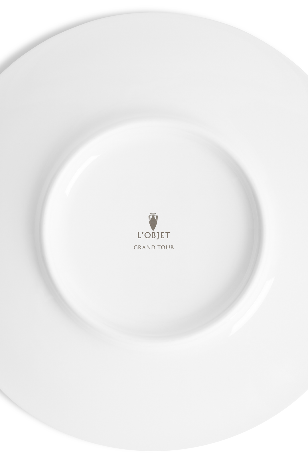 The white underside of a dish with the L'Objet logo and the words "grand tour" inscribed
