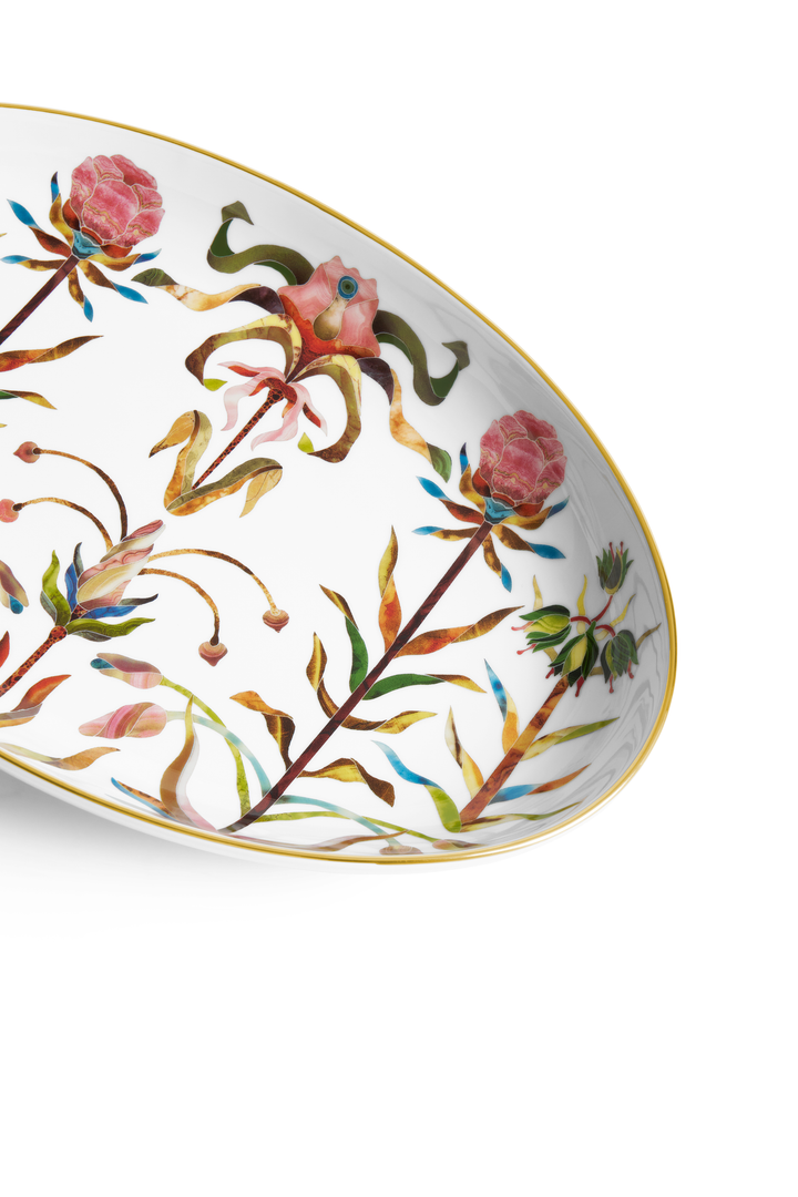 A closeup of a porcelain saucer with a gold rim and painted floral motifs