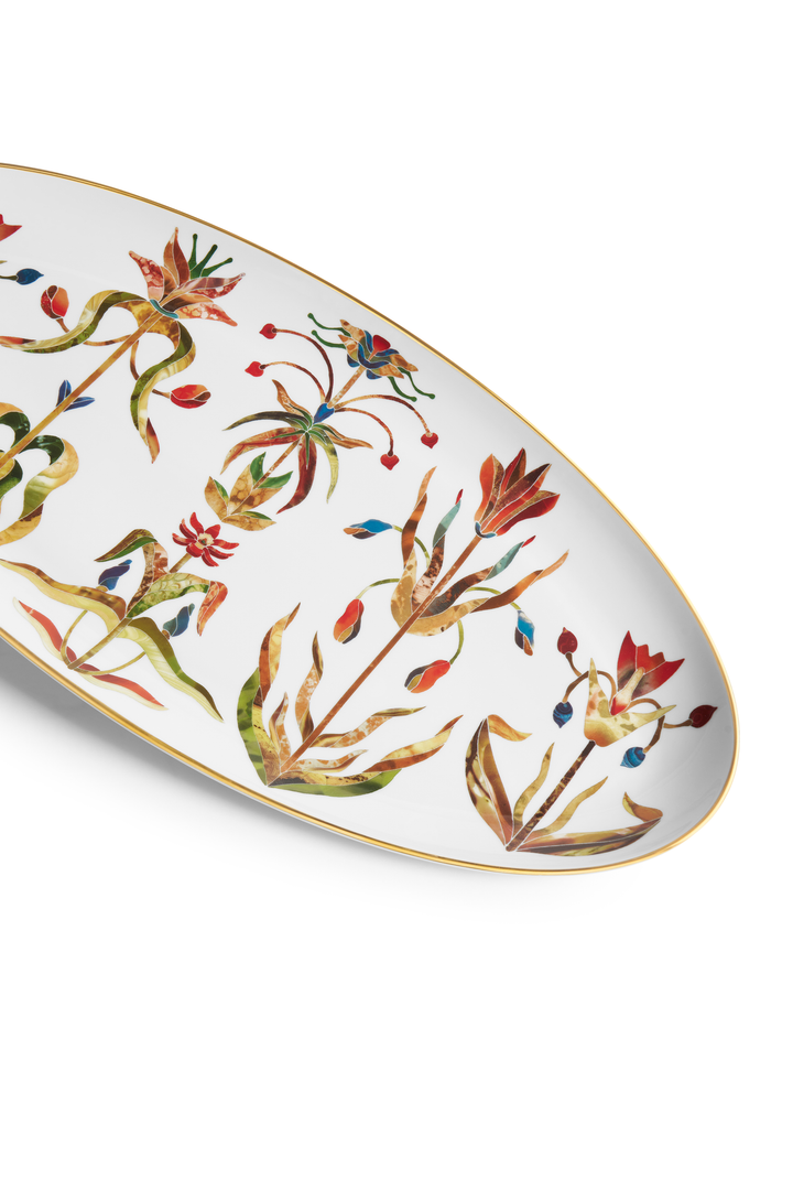 A closeup of a white porcelain painted platter with painted floral motifs and a gold rim 