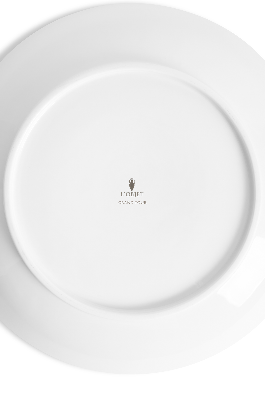 the bottom of a porcelain saucer with the L'Objet logo and the words "grand Tour" etched into the bottom 