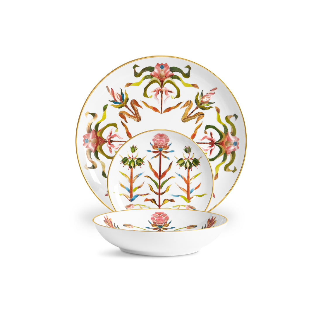 A porcelain dinner plate, side plate, and bowl with painted floral designs and a gold rim.
