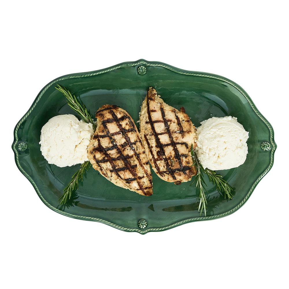 Grilled chicken breasts on a green plate with white rice and rosemary.