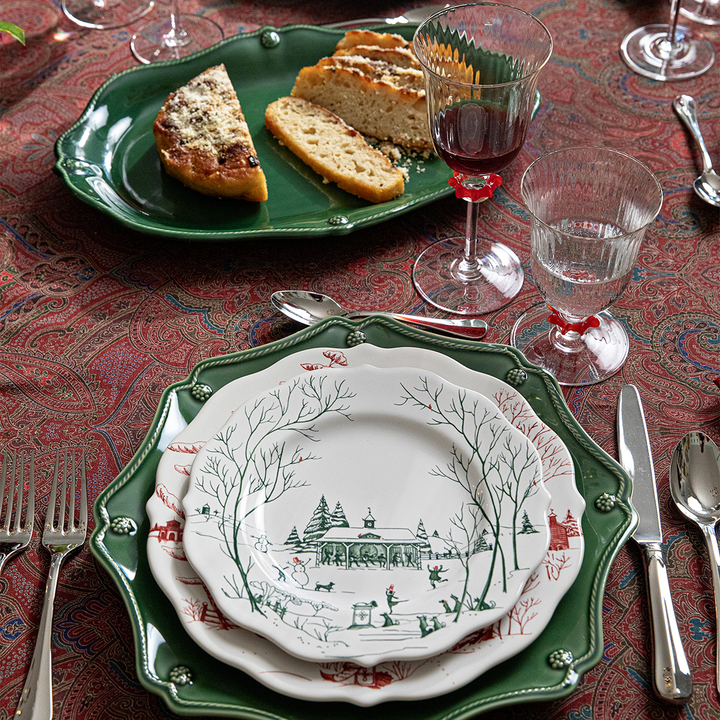 Set table with decorative plates, glasses, and cutlery on a patterned tablecloth.