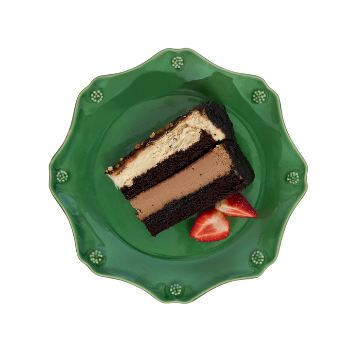 Slice of layered cake on a green plate with strawberries