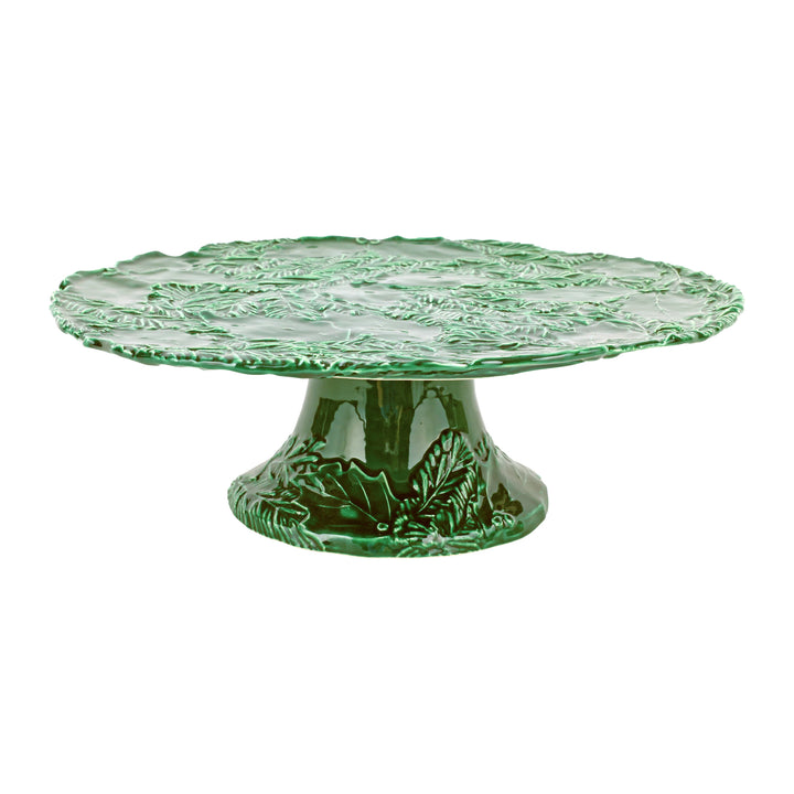 Green ceramic cake stand with holly design on a white background