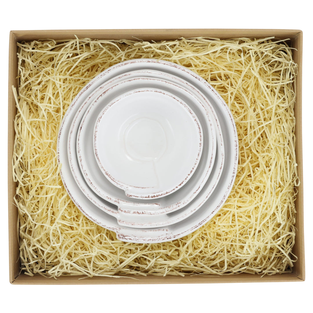 Set of four white nesting bowls in a box with shredded paper