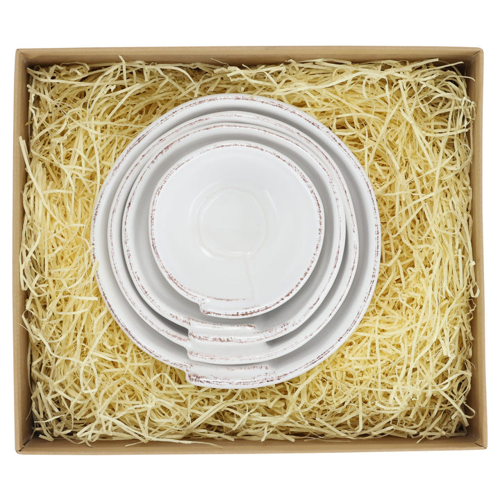 Set of four white nesting bowls in a box with shredded paper