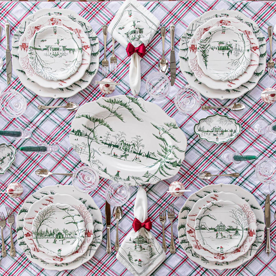 Decorative Christmas table setting with green patterned white plates and plaid tablecloth