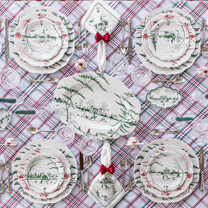 Decorative Christmas table setting with green patterned white plates and plaid tablecloth