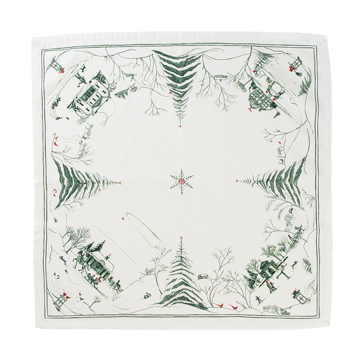A square white fabric napkin featuring a winter village scene printed in dark green and small red accents, with pine trees, cabins, and a star motif in the center.