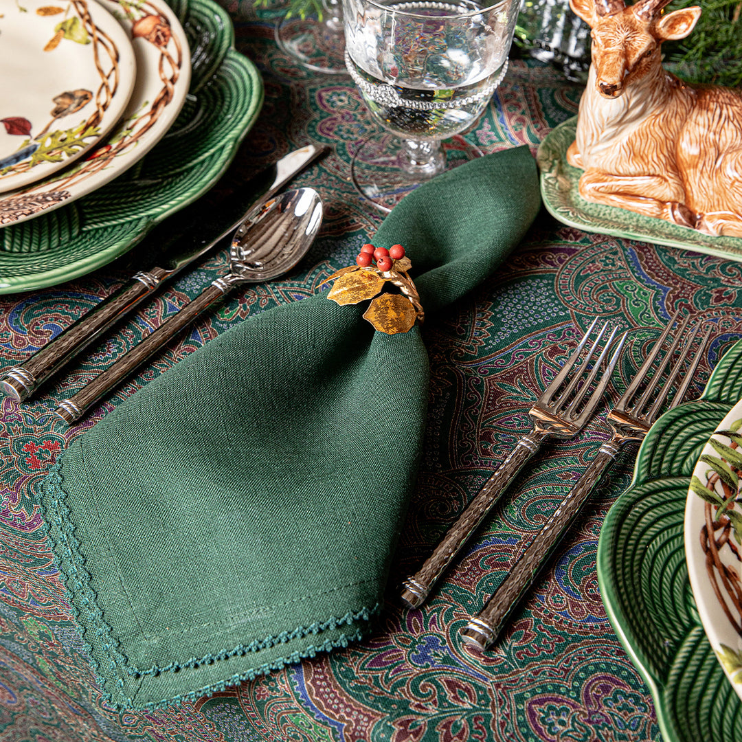 Decorative table setting with green napkin, silverware, and patterned tablecloth.