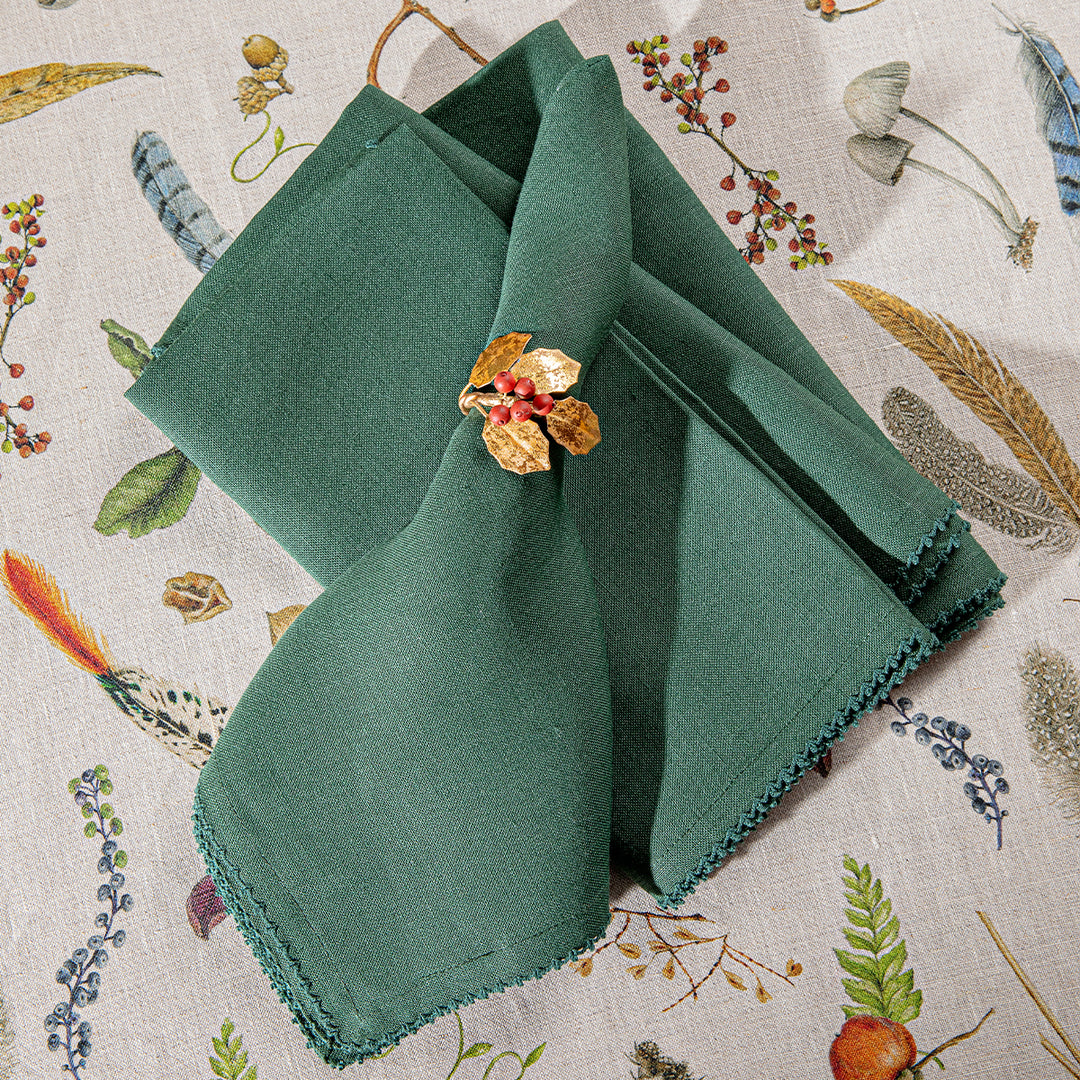 Green folded napkin with a decorative brooch on a floral-patterned background