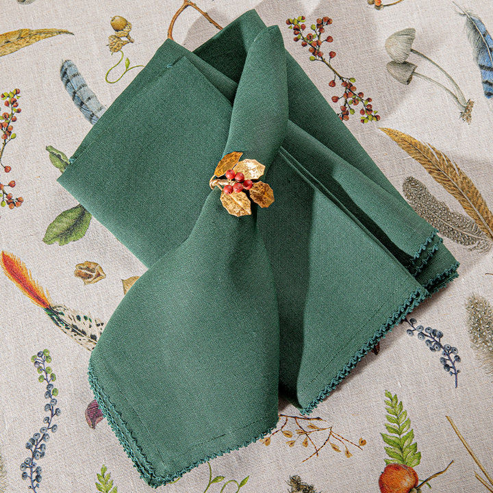 Green folded napkin with a decorative brooch on a floral-patterned background
