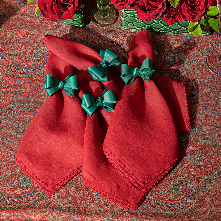 Red napkins with green bows on a patterned tablecloth