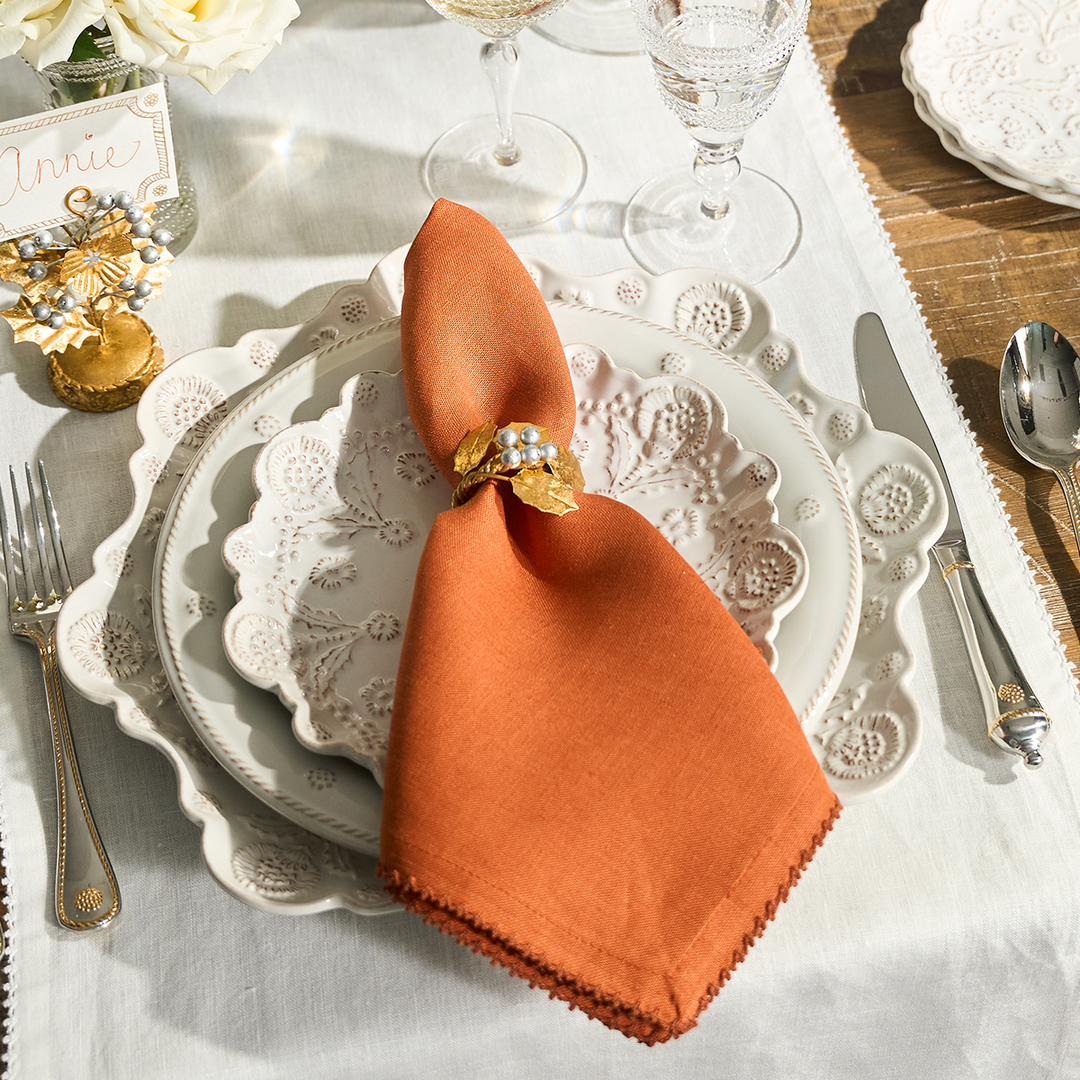 Elegant table setting with an orange napkin on a white plate.
