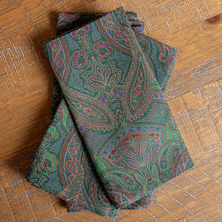 Folded green paisley fabric on a wooden surface