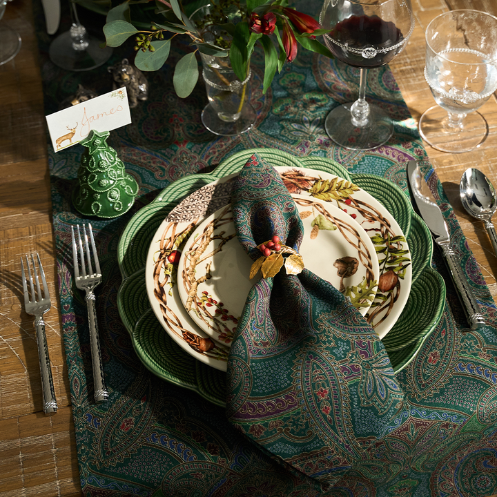Elegant table setting with decorative plates, napkin, and cutlery on a patterned tablecloth.
