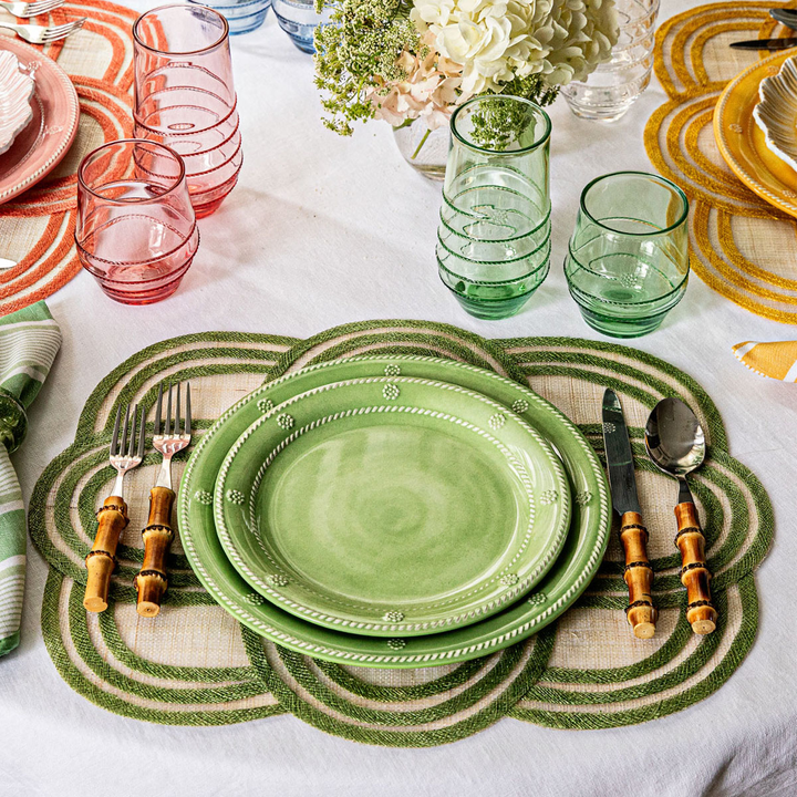 Green ceramic plates with cutlery on a decorative placemat with green tableware 