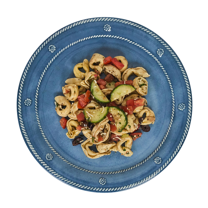 Blue plate with pasta dish featuring vegetables
