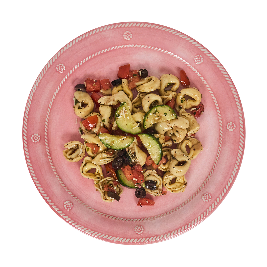 Pasta salad with vegetables on a pink plate