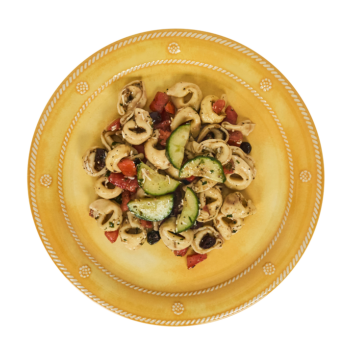 Pasta dish with vegetables on a decorative yellow plate