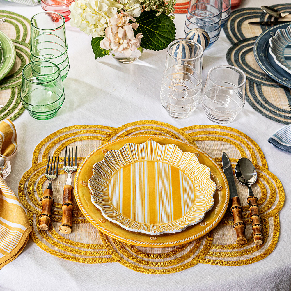 Dining table setting with yellow striped plates, cutlery, and decorative elements.