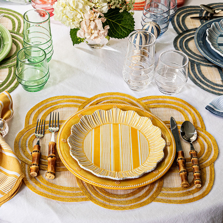 Dining table setting with yellow striped plates, cutlery, and decorative elements.