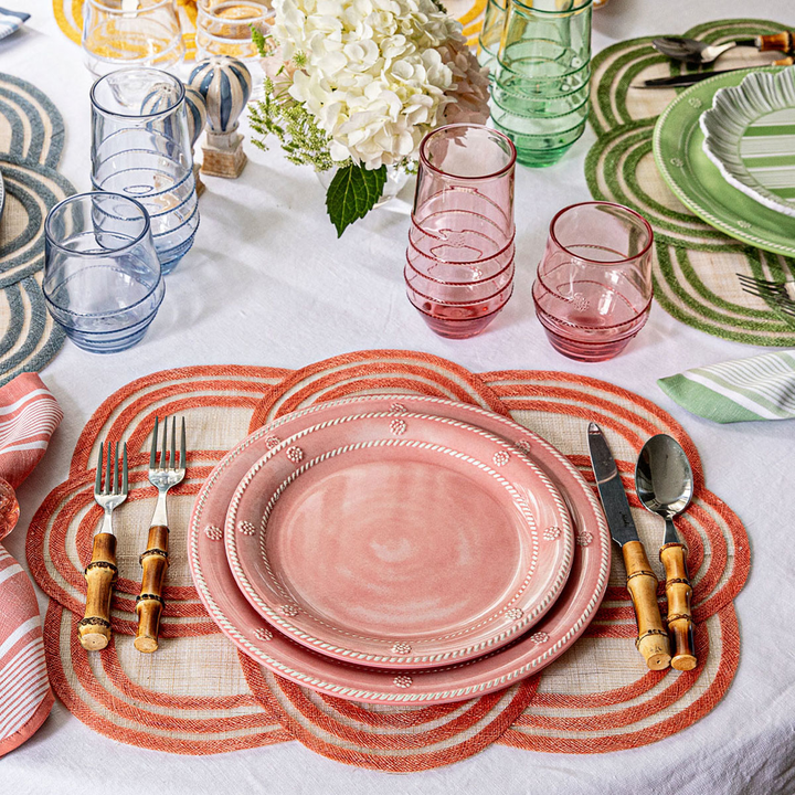 Dining table setting with pink plates, glasses, and cutlery
