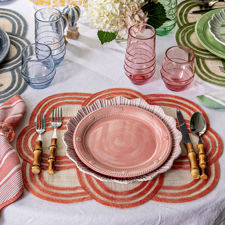 Dining table setting with pink plates, glasses, and cutlery
