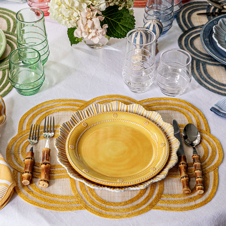 Dining table setting with yellow plates, cutlery, and decorative placemats.
