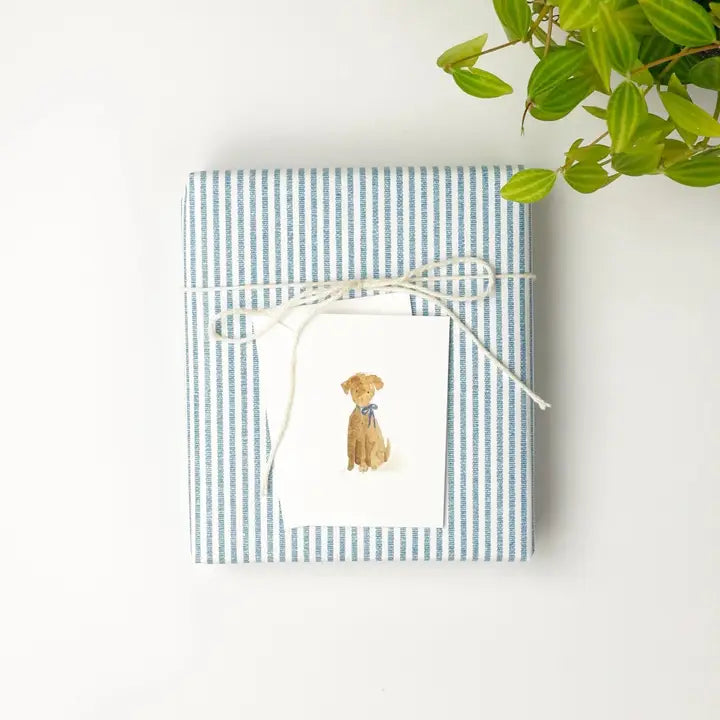 Gift wrapped in blue and white striped paper with a dog illustration, tied with white string on a white background.