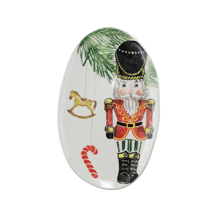 Decorative oval platter with a nutcracker design, candy cane, and rocking horse on a white background