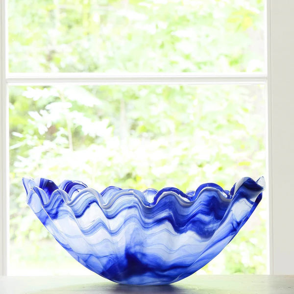 Blue glass bowl on a table with a window in the background