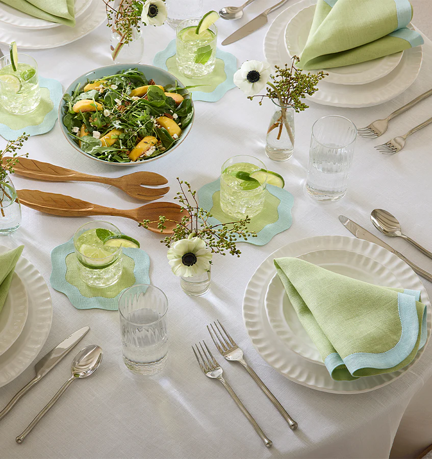 A tablescape with sferra green and blue dinnner napkins and coaters with wavy edges