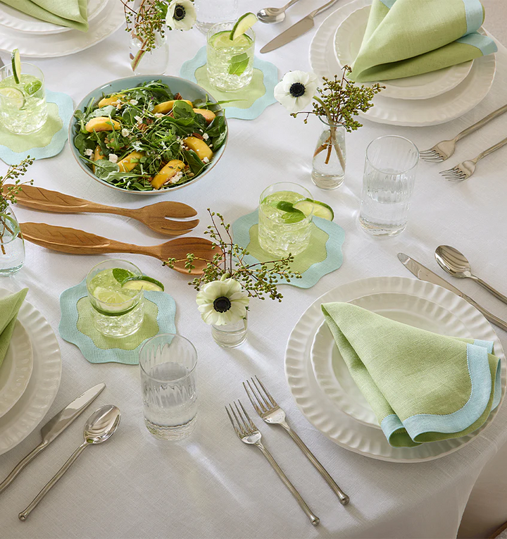 A tablescape with sferra green and blue dinnner napkins and coaters with wavy edges