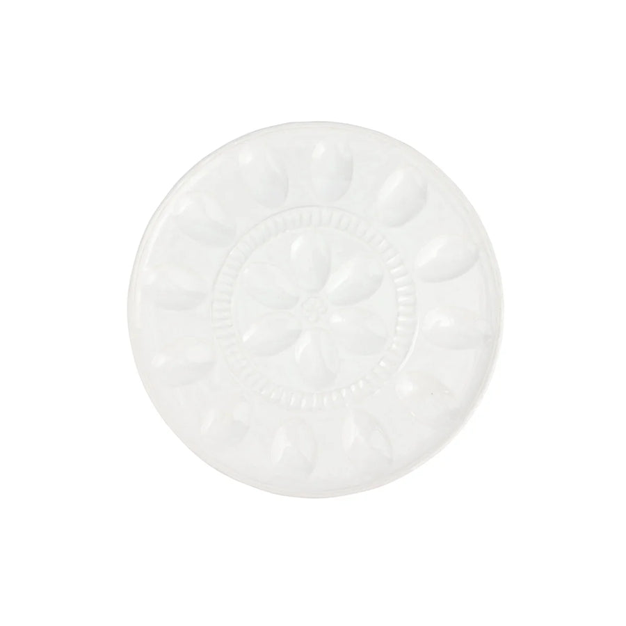 A round white ceramic plate with a raised floral pattern in the center and petal-like indentations around the rim, shown on a plain white background.