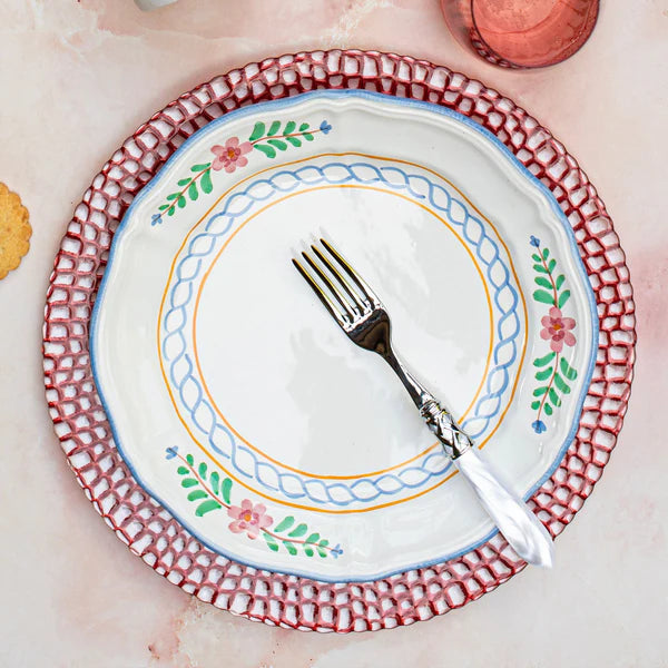 Decorative plate with floral patterns and a fork on a pink surface