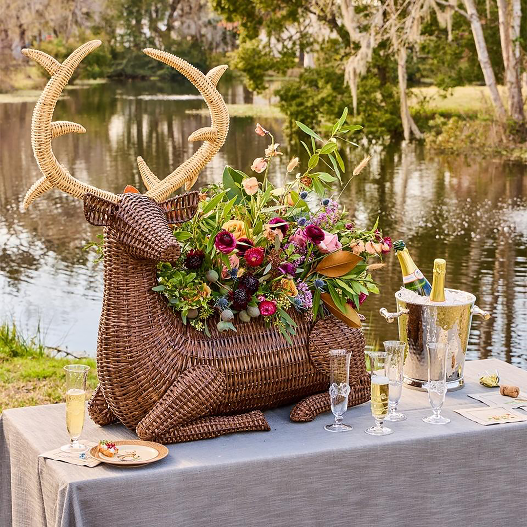 Decorative wicker deer with floral arrangement on a table by a lake