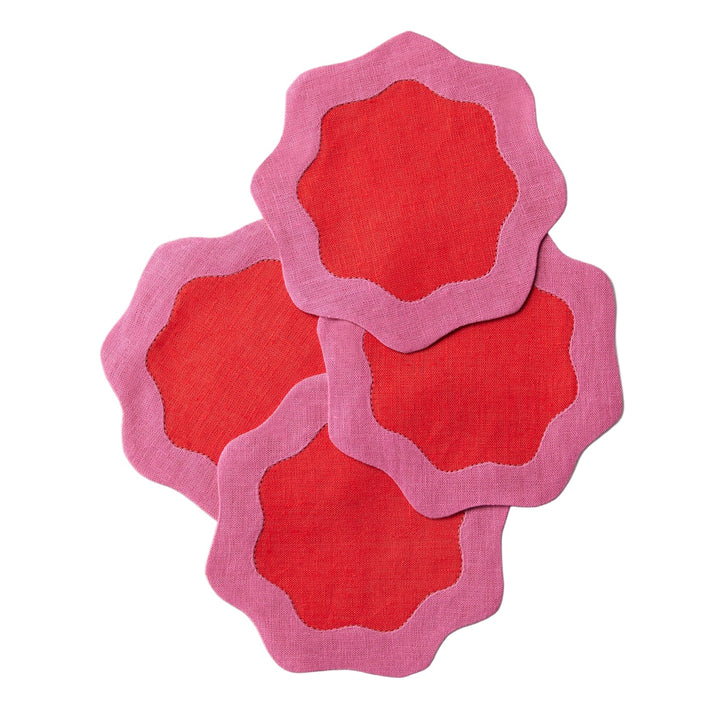 Four red coasters with pink wavy edges on a white surface